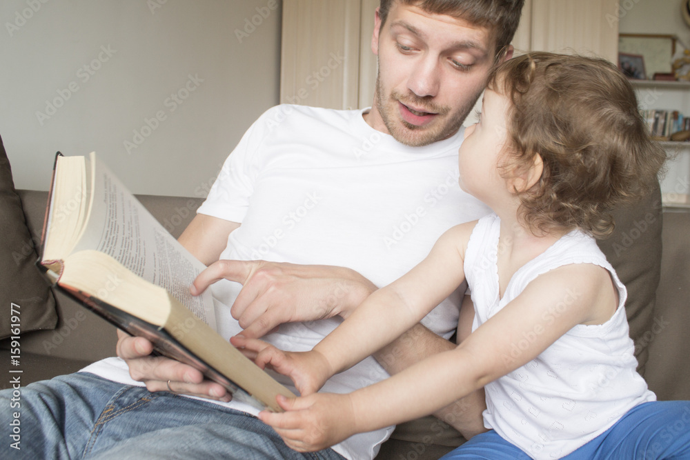 Dad is reading a book with a child. Young father. Father's Day Dad is reading a book with a child. Young father. Father's Day