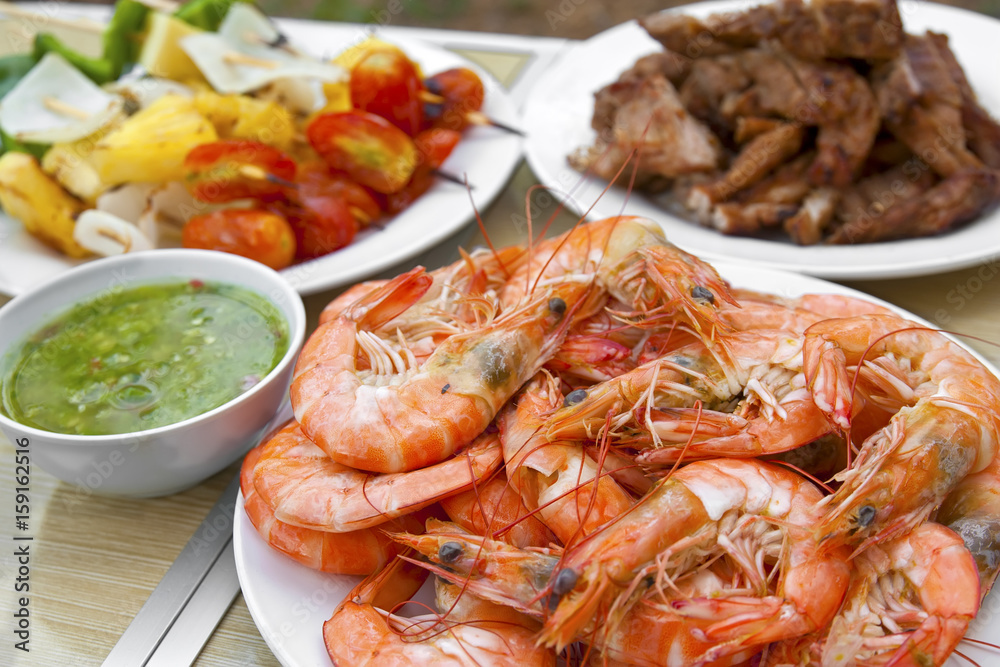 grilled or baked shrimp and pork with vegetable barbecue BBQ and seafood sauce in white dish and wood table on summer holiday picnic for dinner food