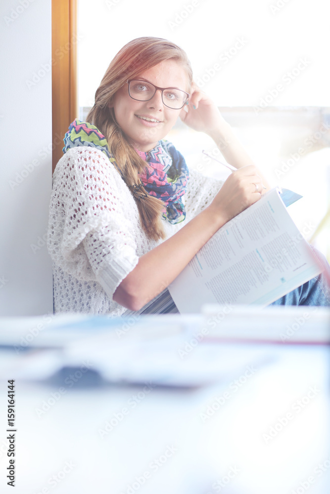 Young woman sitting at a desk among books. Student Young woman sitting at a desk among books. Student