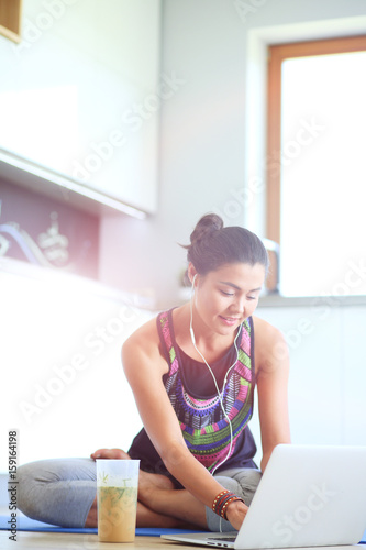 Sporty smiling woman using laptop in bright room. Woman. Lifestyle photo