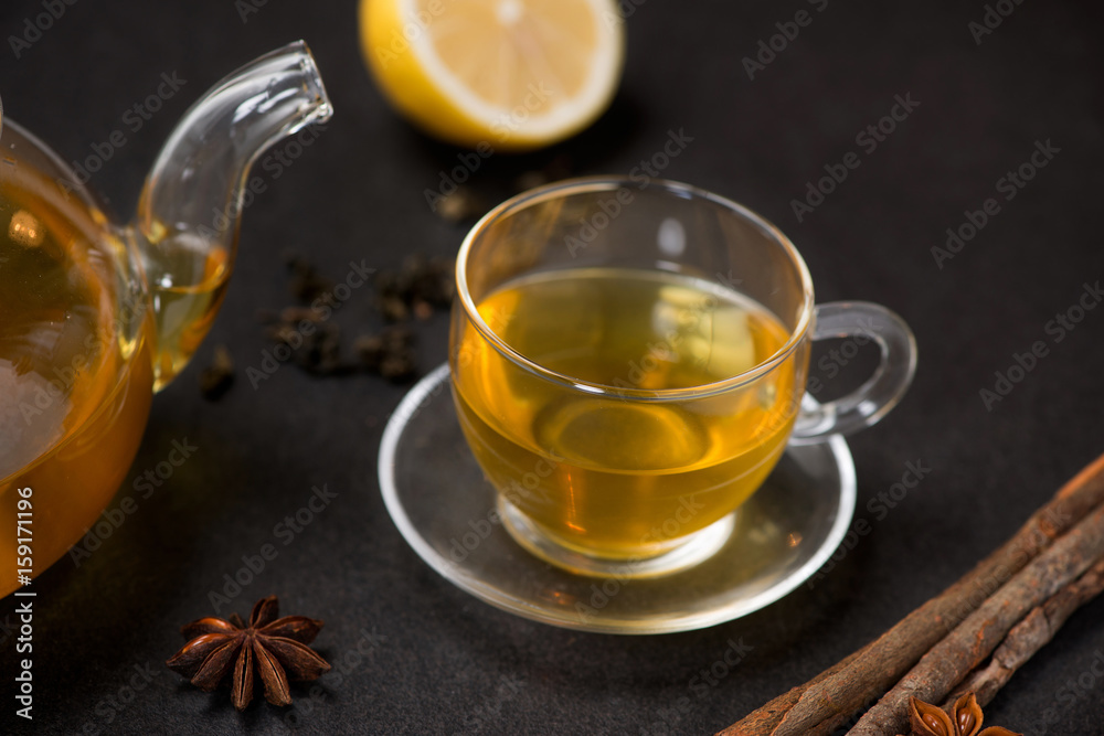 Cup of ginger tea with lemon and honey on dark stone background