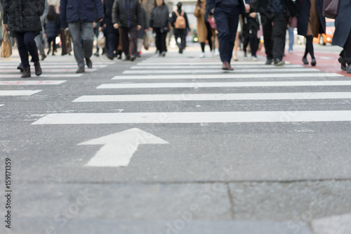 A lot of people are walking on the crosswalk in big city streets.