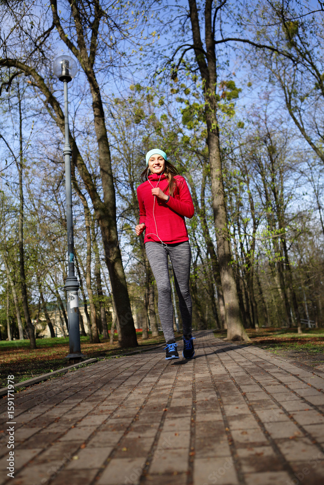 Happy young woman running to the park on the pavement, healthy lifestyle Happy young woman running to the park on the pavement, healthy lifestyle