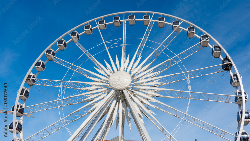 Ferris wheel rotating on blue sky background.