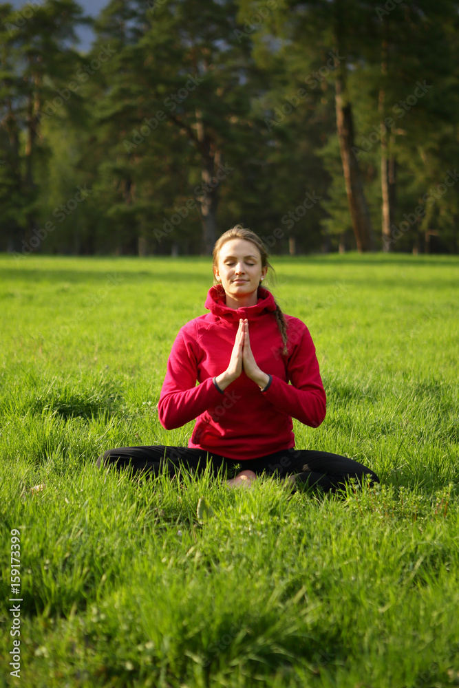 Yoga meditating woman in green grass, nature, park, forest, healthy lifestyle