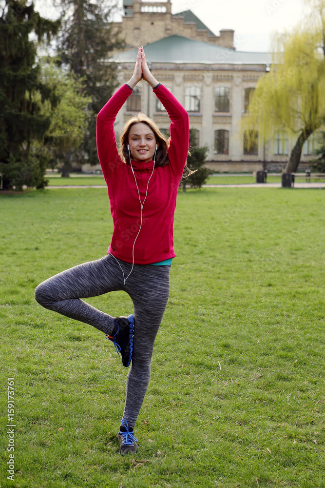 Beautiful yoga woman exercising on green grass, balance on one leghealthy lifestyle