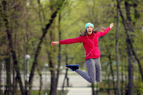 Positive happy sport girl jumping in park, nature, city
