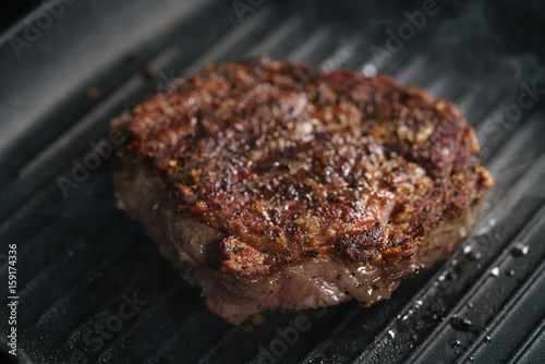 beef rib eye steak on grill pan closeup, shallow focus