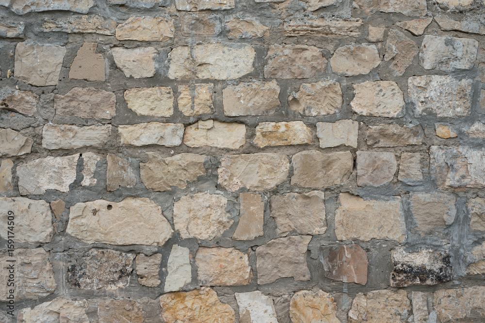 Fototapeta premium Gray decorative uneven cracked stone wall surface with cement