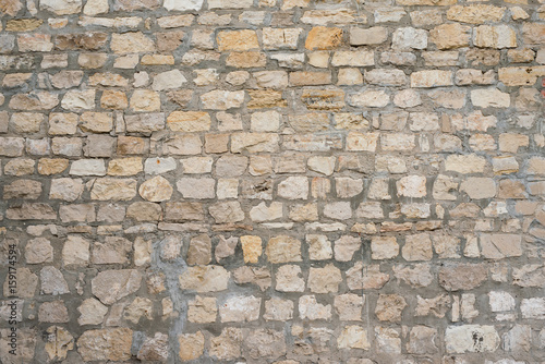 Part of a uneven stone wall with cement Background, texture