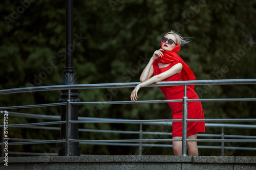Fototapeta Naklejka Na Ścianę i Meble -  Fashionable woman is bored and waiting, she is fashionably dressed in scarlet dress.