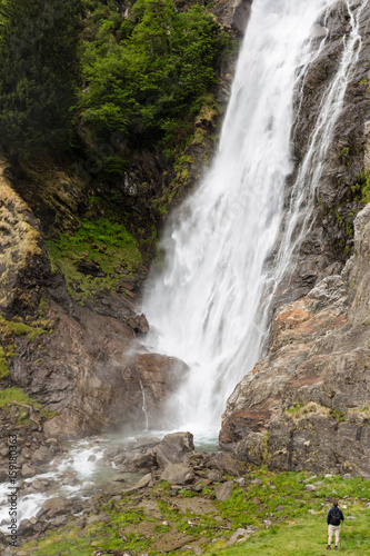 Person vor hohem Wasserfall nahe Meran