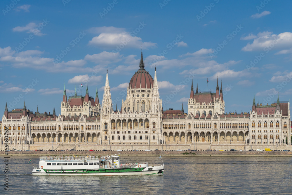 Parlamentsgebäude in Budapest zwischen blauem Himmel und blauer Donau mit Flussdampfer i