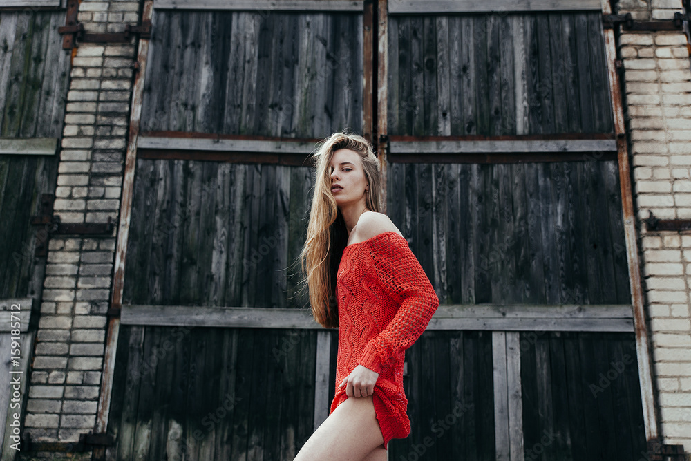 Fototapeta premium The sexy girl in red sweater about a wall