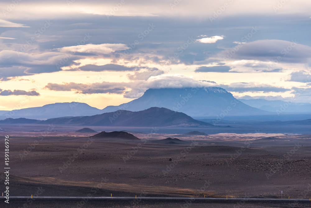 Vast landscape of Iceland, with a distance view of a peak covered by  clouds