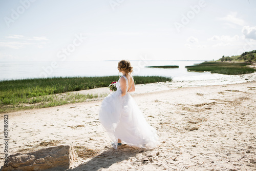 bride in a wedding dress is walking along the beach.