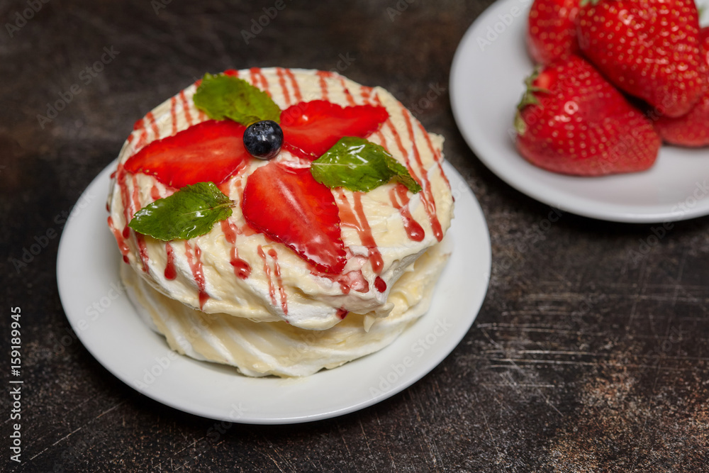 White creamy round cake with strawberries and mint on plate
