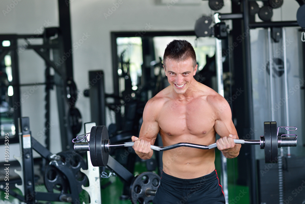 Man at the gym. Man makes exercises with barbell