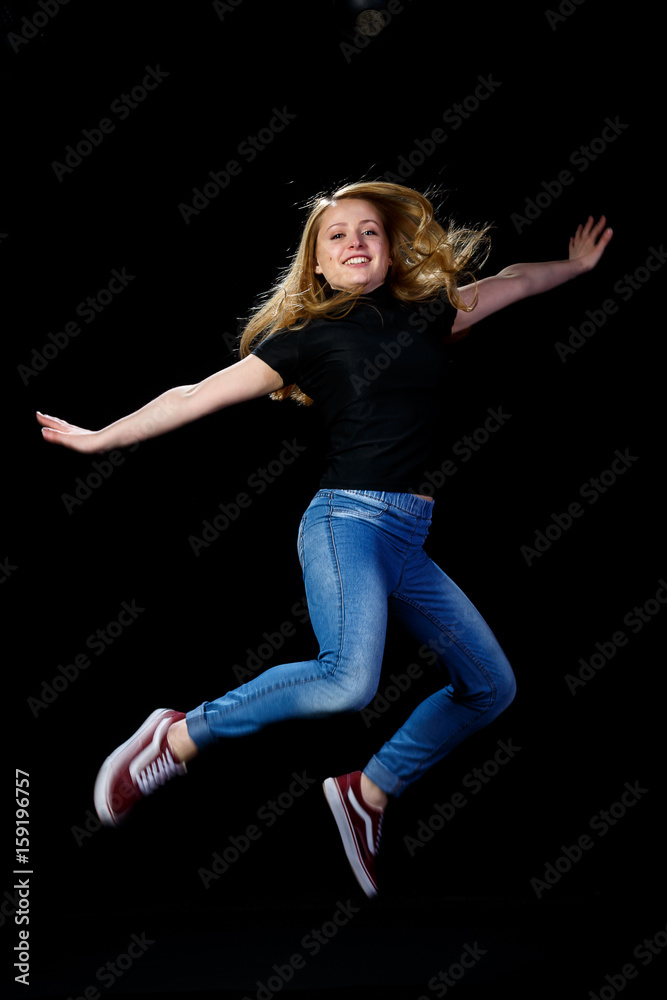 Cheerful young blonde dancing on a black background