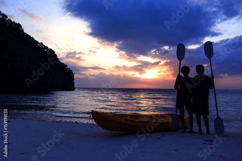 Bild auf Leinwand Silhouette kayaking on the beach with tourist girl looking blue sky sunset