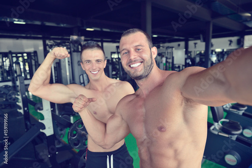 Portrait of two smiling muscular men flexing biceps