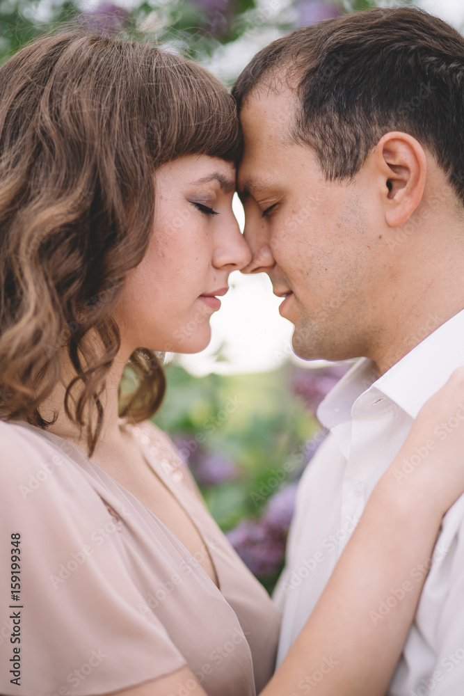 beautiful couple, the girl in beige light dress, the guy the white shirt, cuddling with their eyes closed, foreheads pressed against each other near the tree, greens, summer, lilac, close-up, nature beautiful couple, the girl in beige light dress, the guy the white shirt, cuddling with their eyes closed, foreheads pressed against each other near the tree, greens, summer, lilac, close-up, nature