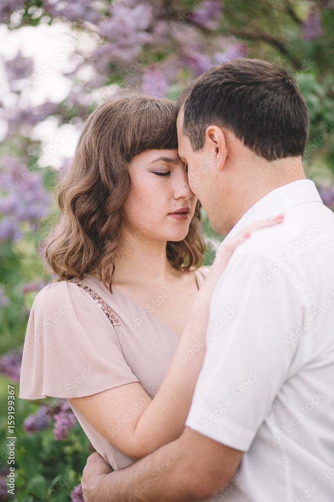 beautiful couple, the girl in beige light dress, the guy the white shirt, cuddling with their eyes closed, foreheads pressed against each other near the tree, greens, summer, lilac, close-up, nature beautiful couple, the girl in beige light dress, the guy the white shirt, cuddling with their eyes closed, foreheads pressed against each other near the tree, greens, summer, lilac, close-up, nature