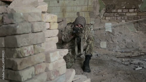Guerilla partisan warrior operation in urban environment. Soldier aiming an enemy with his gun. War battlefield maneuvers training.