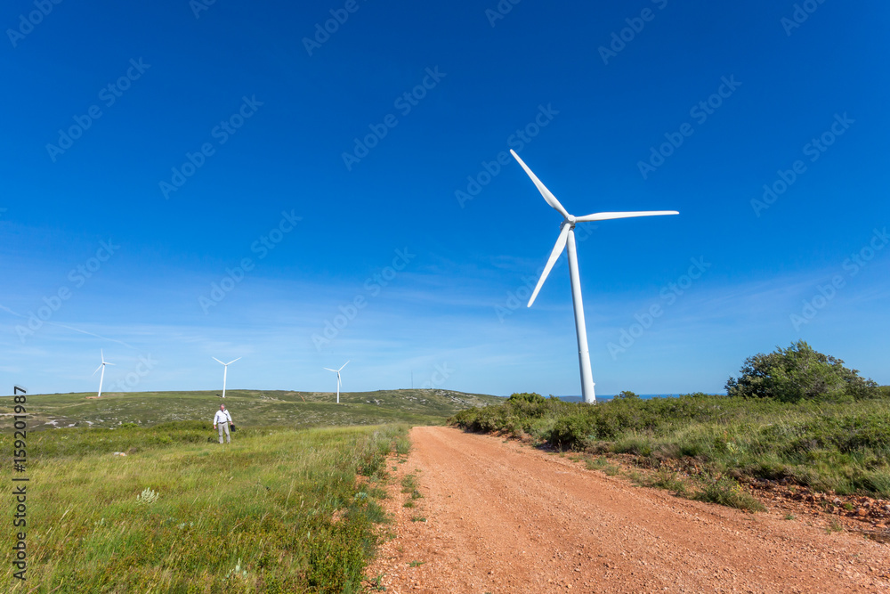 un paysage avec des éoliennes sur le chemin de crête d'une colline et un homme en chemise blanche et cravate et son cartable un paysage avec des éoliennes sur le chemin de crête d'une colline et un homme en chemise blanche et cravate et son cartable