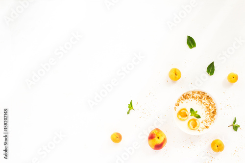 Fresh summer fruit. Healthy breakfast with peach, nectarine, apricot, muesli, peach yogurt, mint, cereal on white background. Flat lay, top wiew.