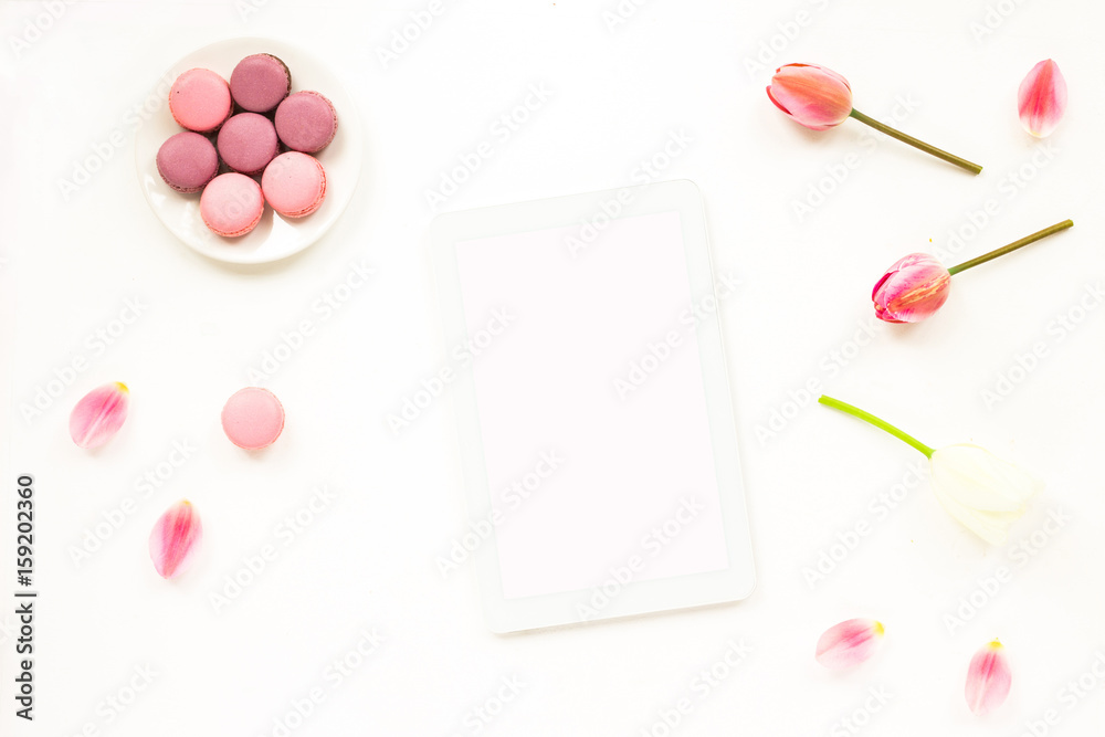 Lilac and white tulip flowers, macaroon cake, tablet on white background. Flat lay, top view Lilac and white tulip flowers, macaroon cake, tablet on white background. Flat lay, top view