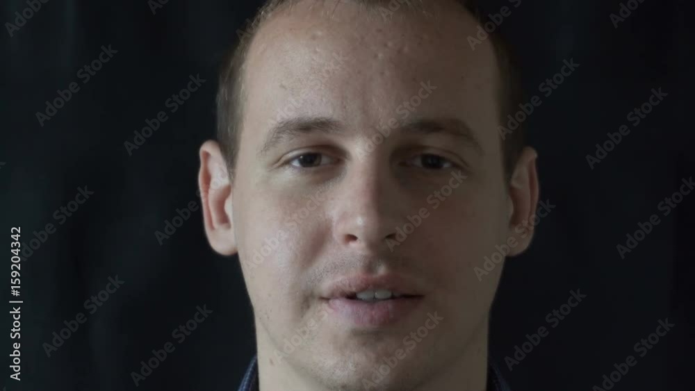A young man smiles on a black background. A young man smiles on a black background.