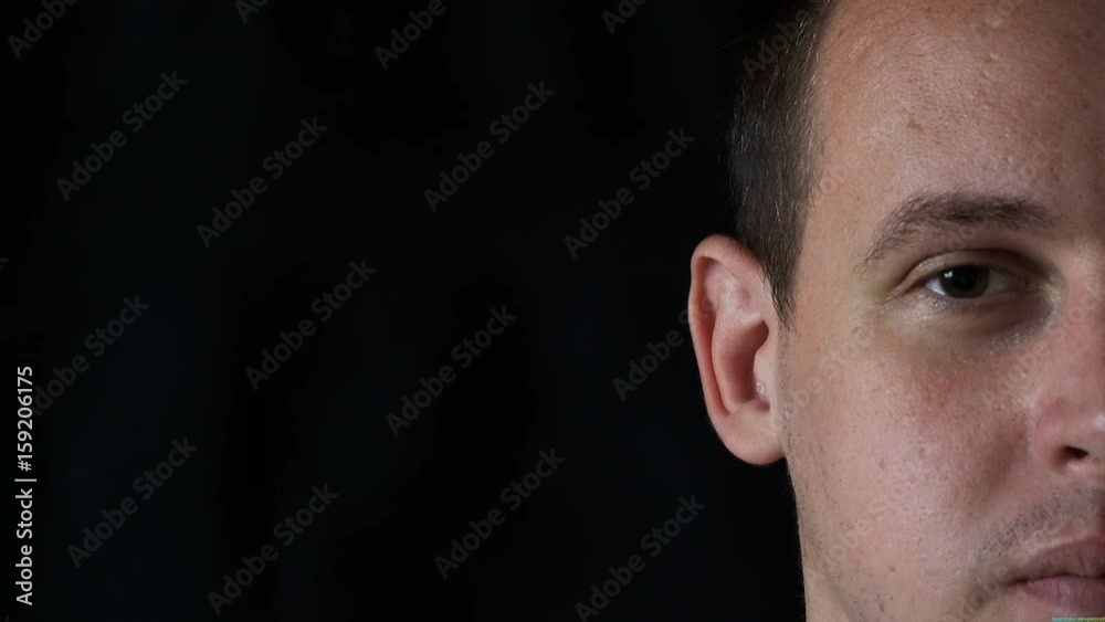 portrait of a young man staring at camera,black background. portrait of a young man staring at camera,black background.