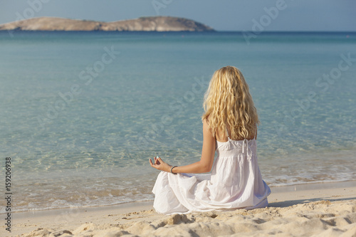 young woman practicing yoga on the beach