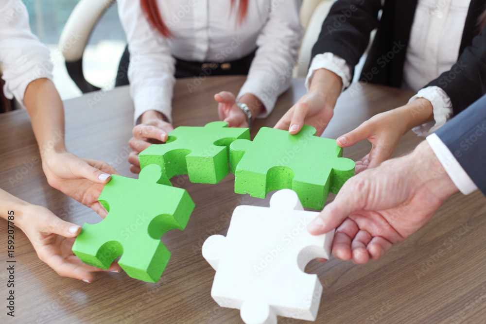 Business people assembling puzzle Business people assembling puzzle