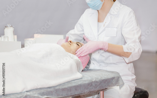 Beautician performs cosmetic procedures and applying cream in Cosmetology clinic