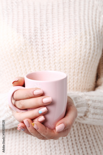 Woman hands with manicure holding cup of coffee