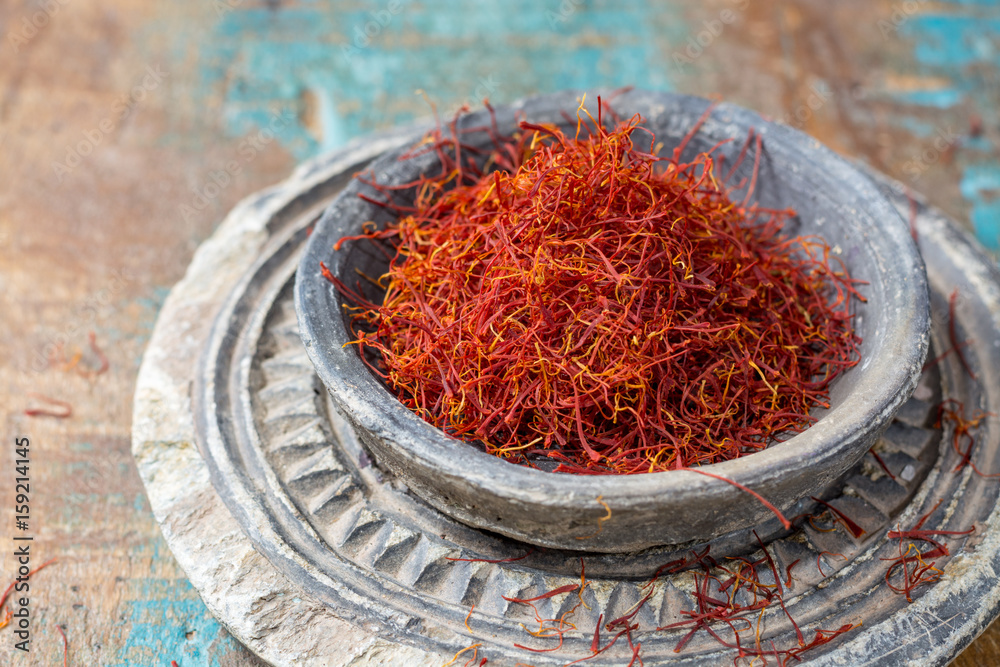 Fototapeta premium Dried organic red saffron Spice in a stone bowl on wooden background