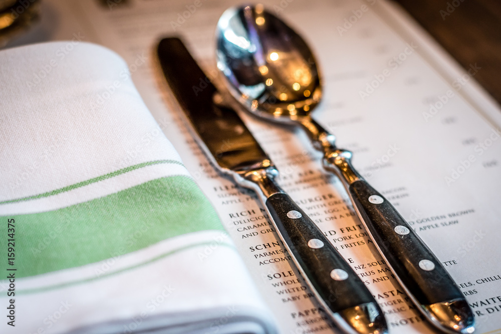 Knife and spoon cutlery and linen napkin menu on table