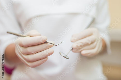 dental instruments in the hands of the doctor. Dentist in sterile latex gloves holding dental tools detail shoot