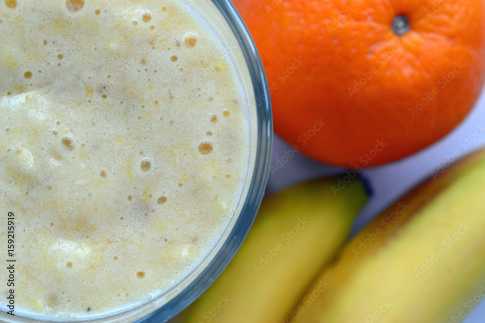 A composition of bananas and orange and a glass with smoothies A composition of bananas and orange and a glass with smoothies