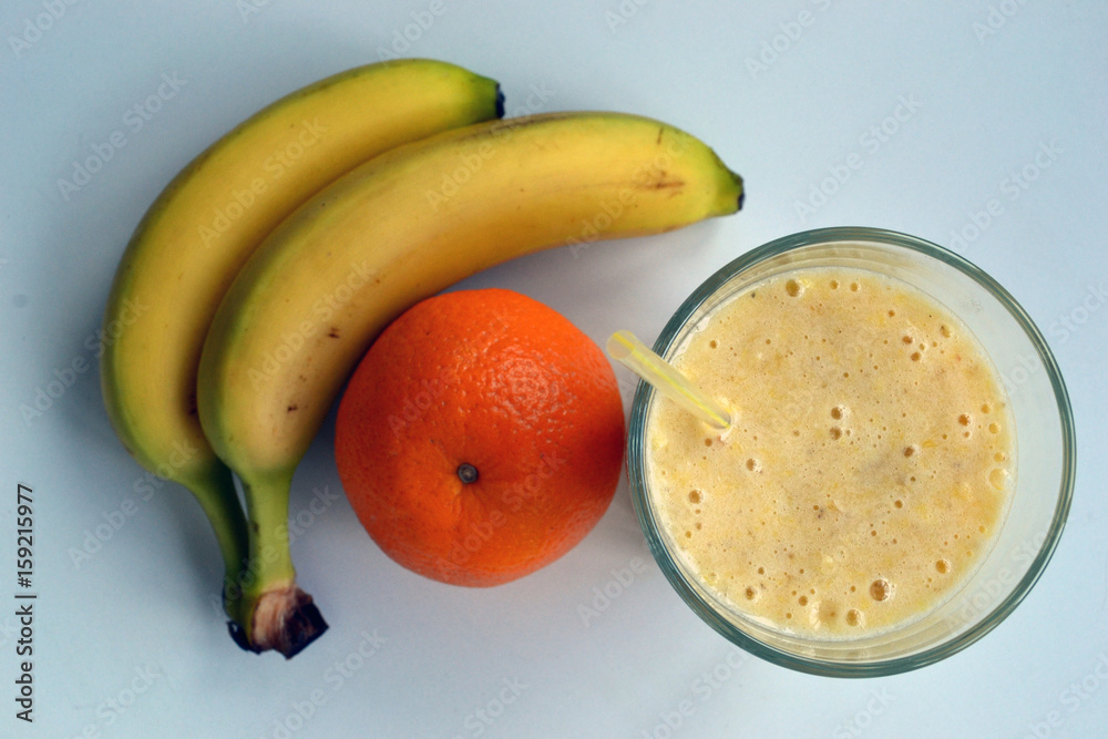 A composition of bananas and orange and a glass with smoothies A composition of bananas and orange and a glass with smoothies