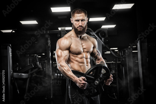 Attractive tall muscular bodybuilder doing heavy deadlifts in moder fitness center. © romanolebedev