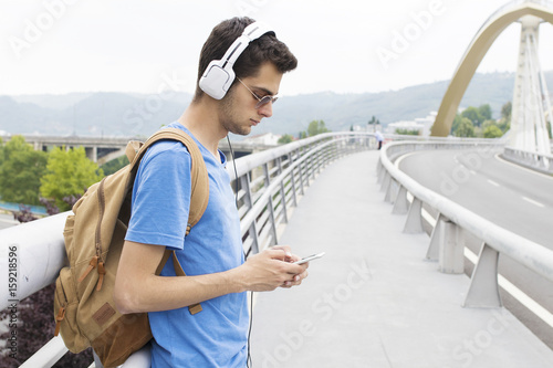 young man with the headset and the phone in the city