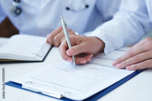 Female doctor filling medical form while consulting patient