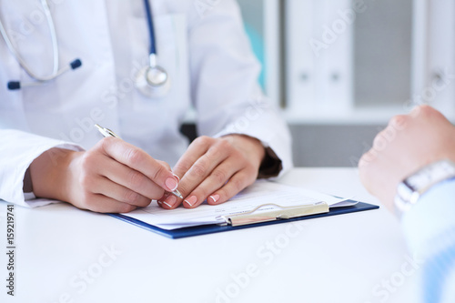 Female doctor filling medical form while consulting patient