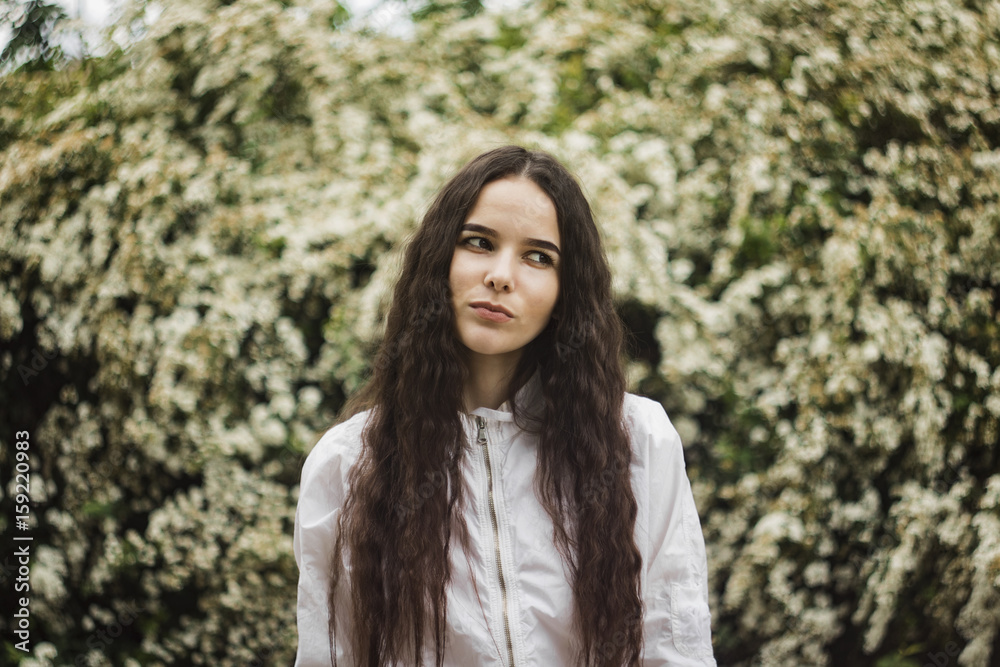 The girl onceived with joy against a white wall of flowers The girl onceived with joy against a white wall of flowers