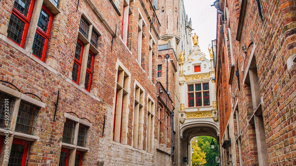 Naklejka premium Bridge crossing between buildings over narrow Blinde-Ezelstraat, aka Blind donkey street, near Burg square, Bruges, Belgium.