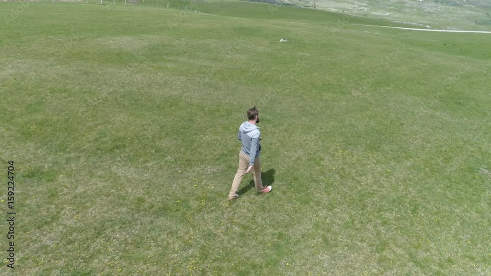 man is walking along the grassy field man is walking along the grassy field