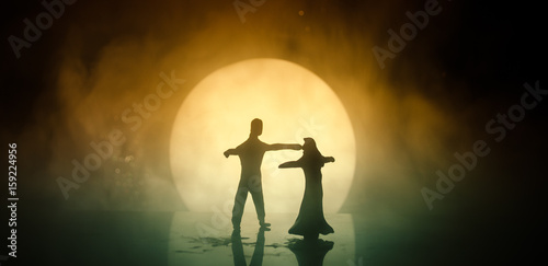 Silhouettes of toy couple dancing under the Moon at night. Figures of man and woman in love dancing at moonlight
